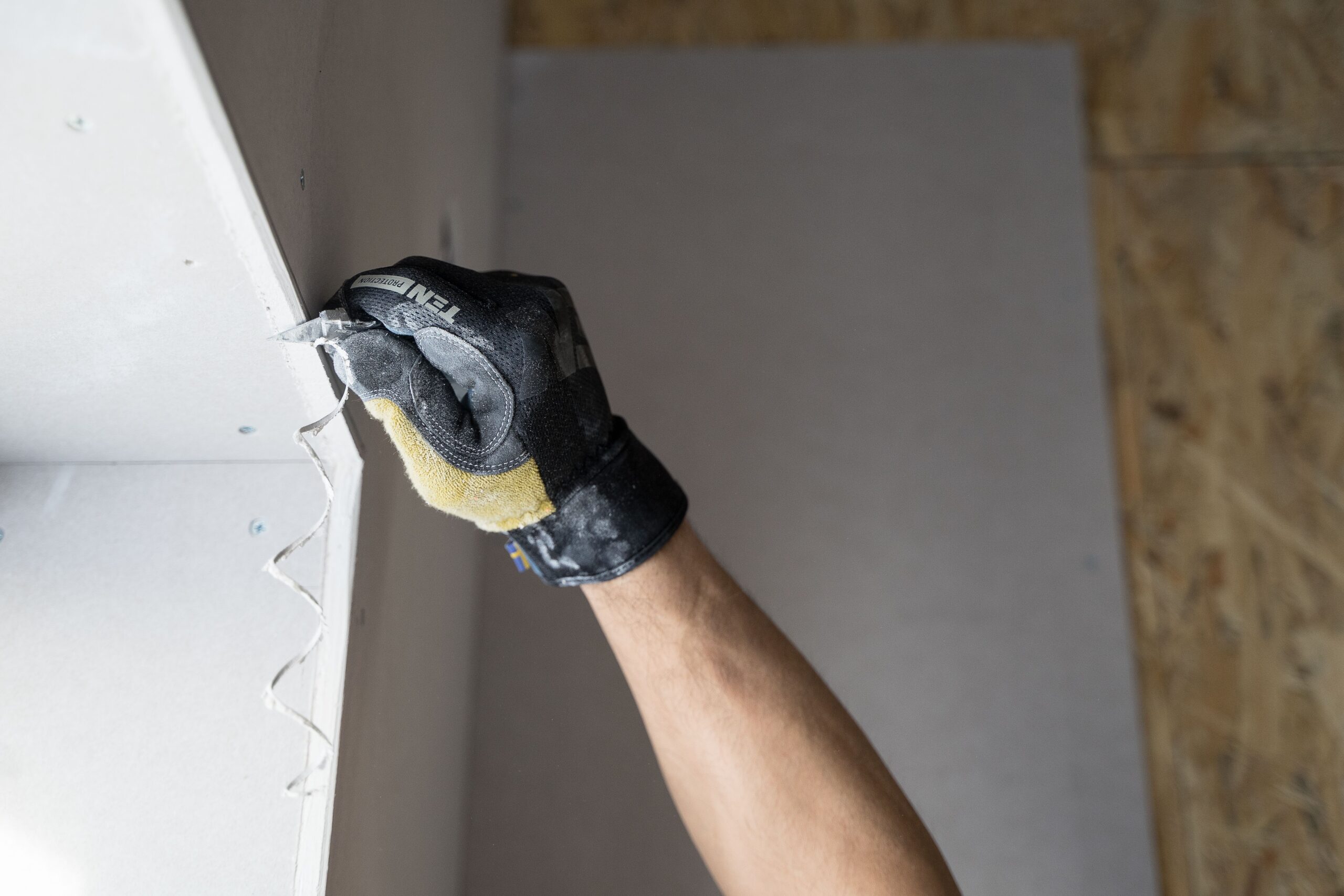 7 Drywall Repair Mistakes Kelowna Homeowners Make (And How to Avoid Them) 2 Close-up of a gloved hand applying plaster to a wall indoors in Falun, Sweden.